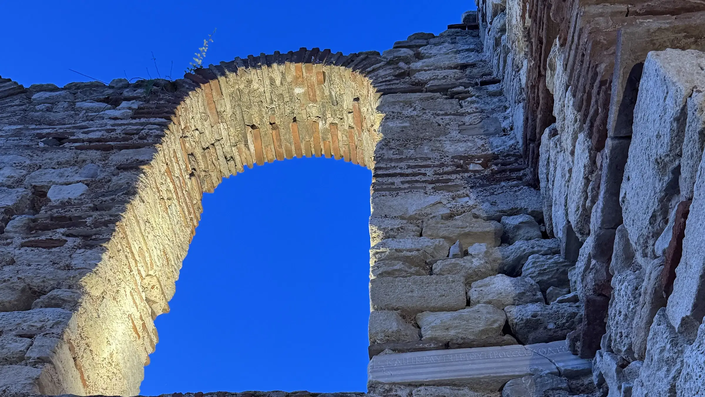 A brick arch of the Old Metropolitan basilica in Nessebar, open to a deep blue sky